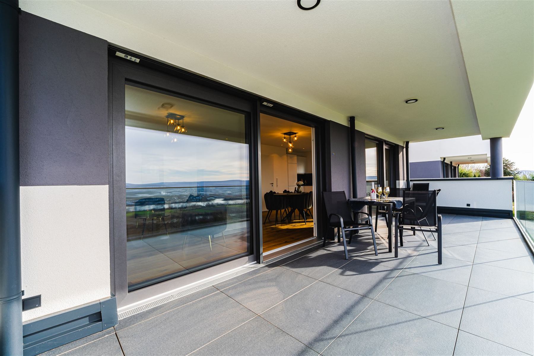 Blick von der Terrasse durch die Glasfront ins beleuchtete Esszimmer
